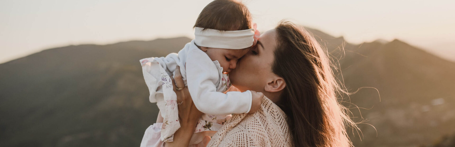 Mutter hält ihr Kind in der Hand und gibt ihm einen Kuss