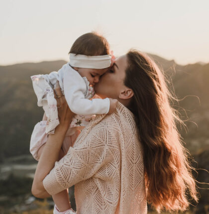 Mutter hält ihr Kind in der Hand und gibt ihm einen Kuss
